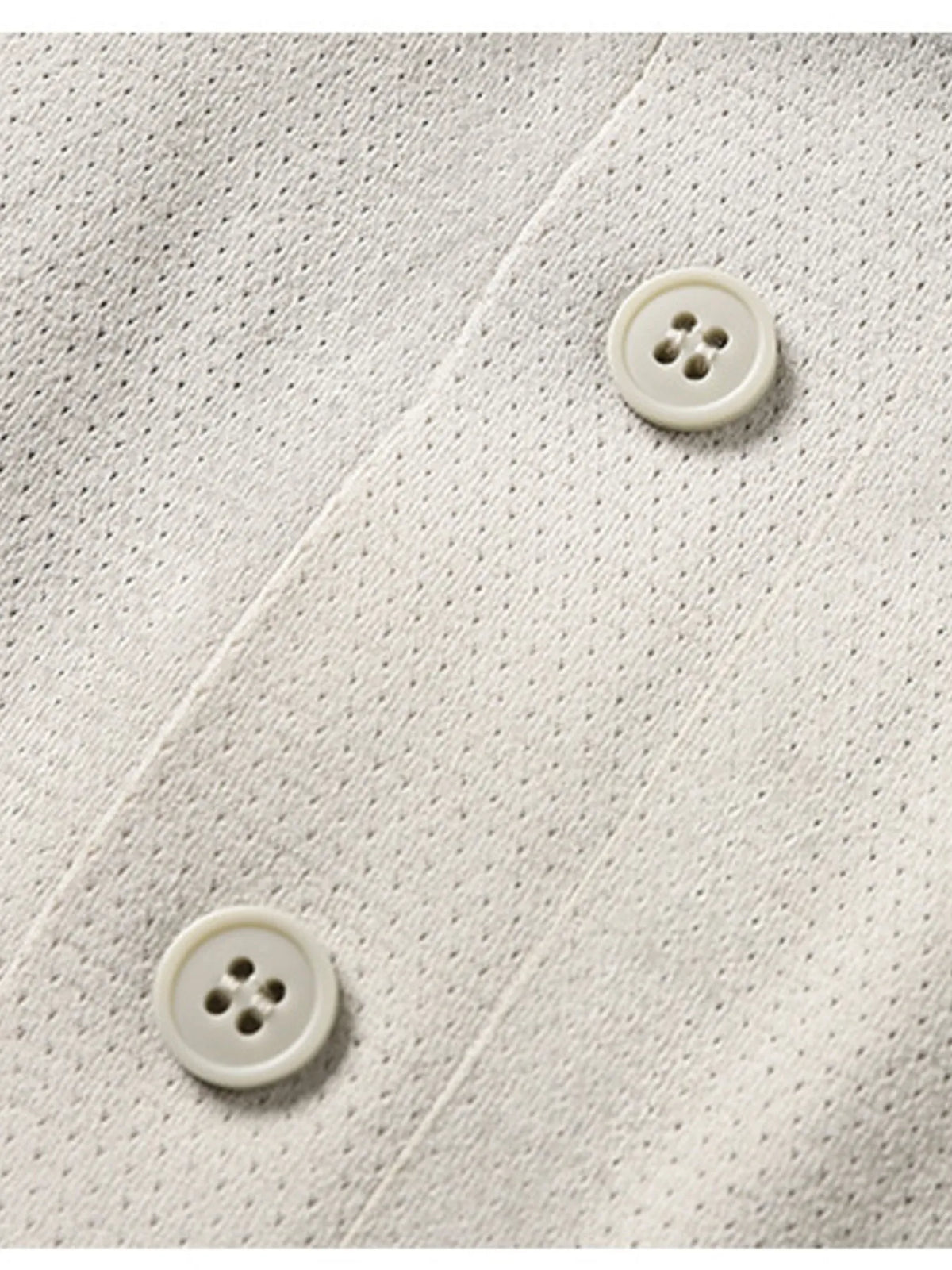 Close-up of a textured white fabric with two buttons on a matching background