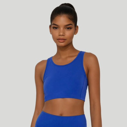 Woman wearing a blue sports bra and leggings on a gray background