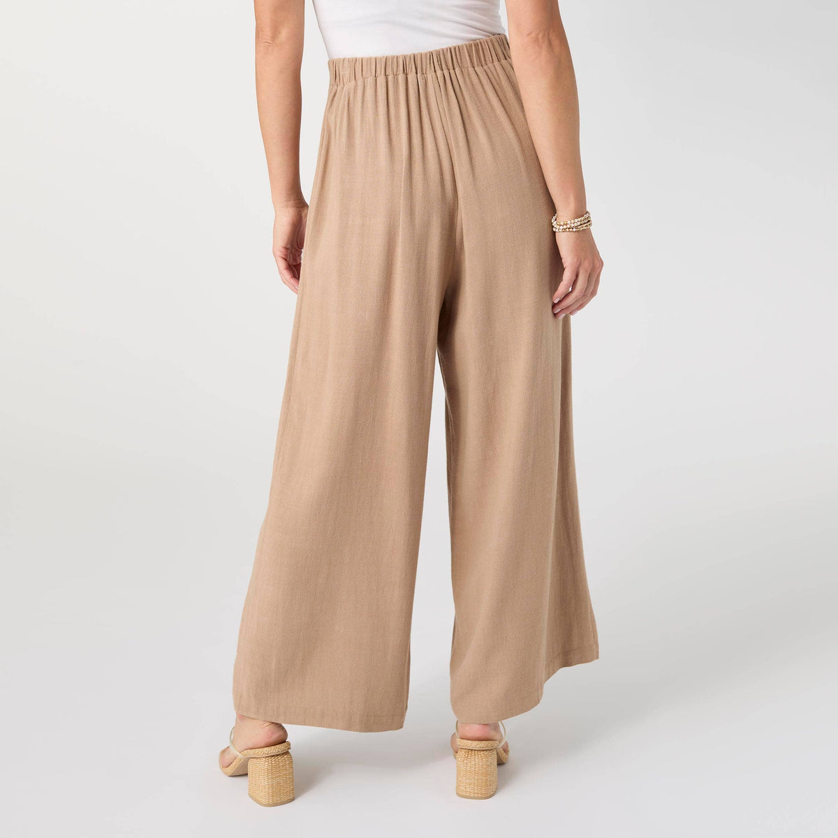 Beige wide-leg pants worn by a person on a white background