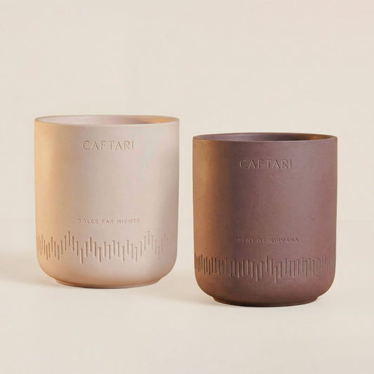Caftari Scent of Nirvana and Dolce Far Niente candles in embossed ceramic vessels, on a beige background