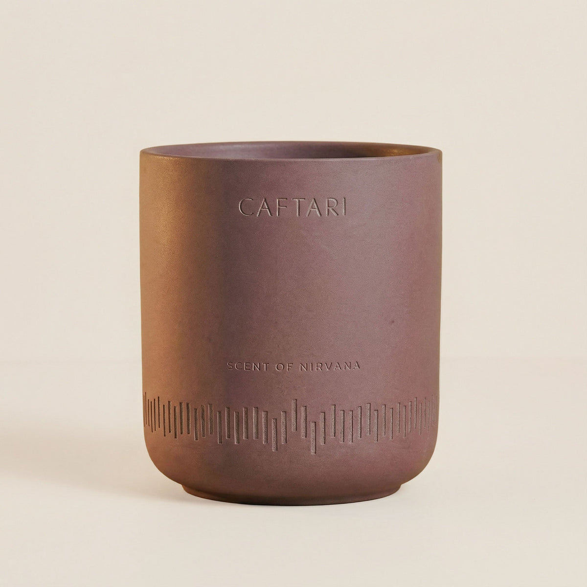 Scent of Nirvana oud candle in its brown ceramic vessel, on a beige background