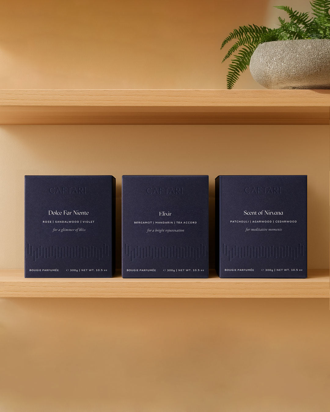 Three boxed Caftari candles — Dolce Far Niente, Elixir and Scent of Nirvana — on a wooden shelf