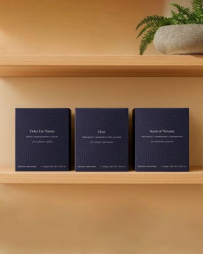 Three boxed Caftari candles — Dolce Far Niente, Elixir and Scent of Nirvana — on a wooden shelf