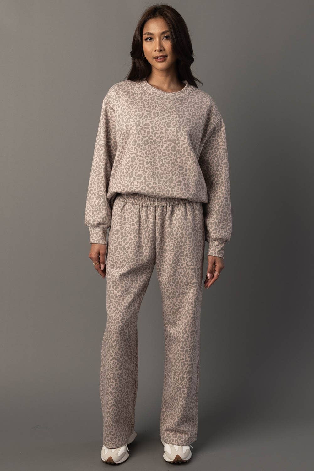 Woman wearing a patterned sweater and pants set against a gray background