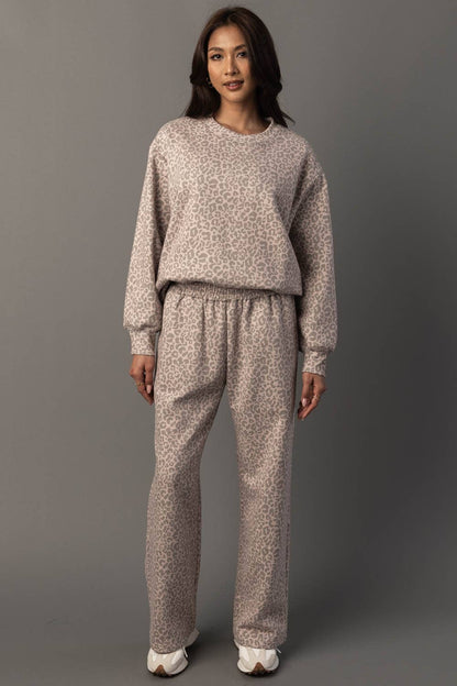 Woman wearing a patterned sweater and pants set against a gray background