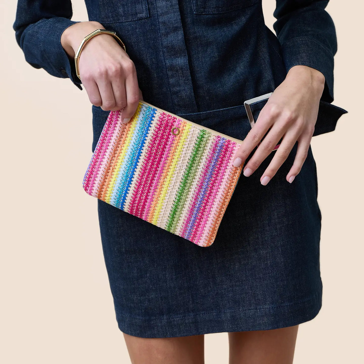 Person holding a colorful striped clutch against a neutral background