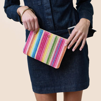 Person holding a colorful striped clutch against a neutral background