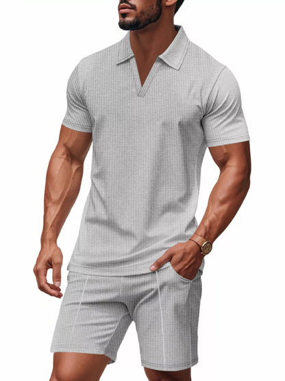 Man wearing a checkered polo shirt and shorts on a white background