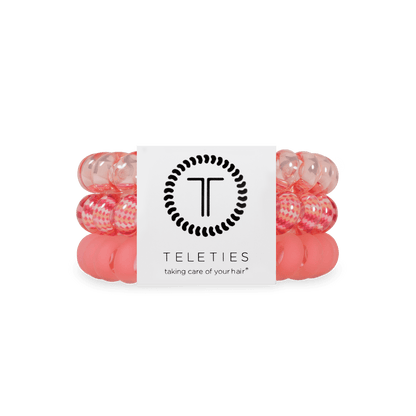 Three pink and translucent hair elastic bands wrapped together with a white paper band featuring the black TELETIES logo and brand name.