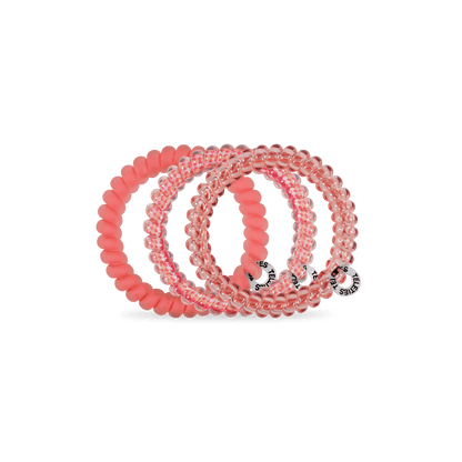 Set of pink hair ties with brand logos on a green background
