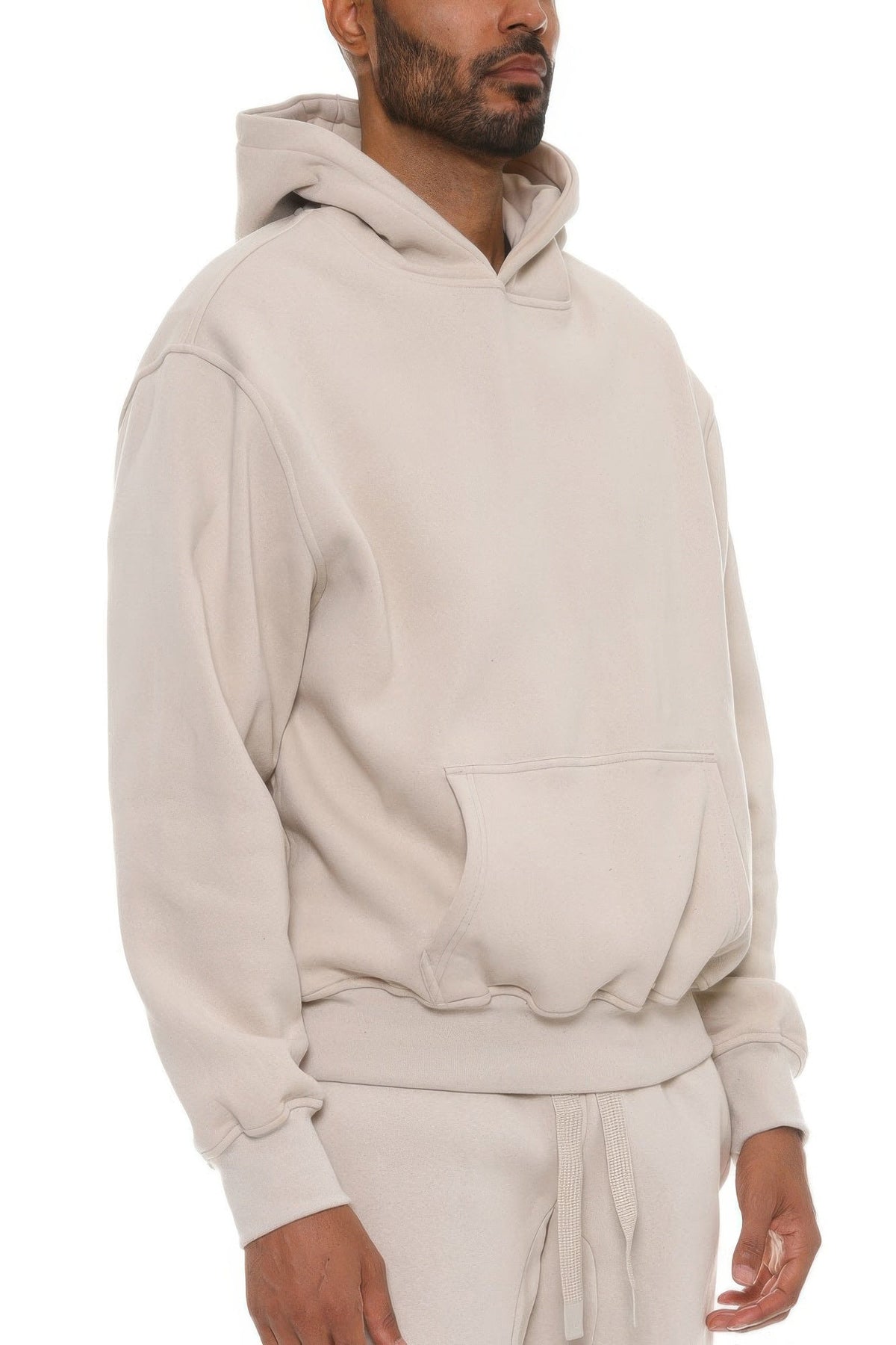 Man wearing a beige hoodie and pants on a white background