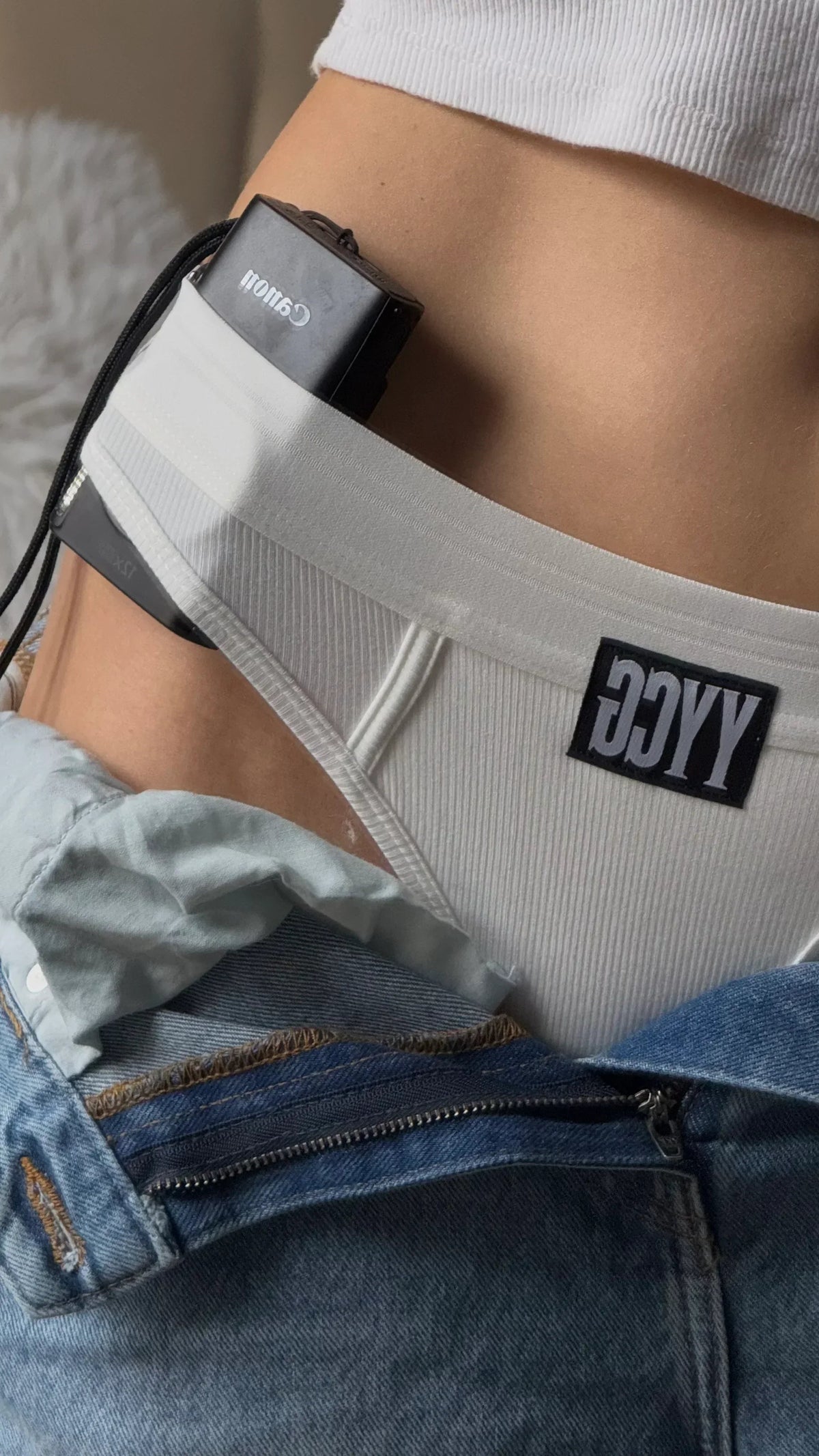 Person wearing white underwear with a visible brand logo, partially covered by a denim jacket.