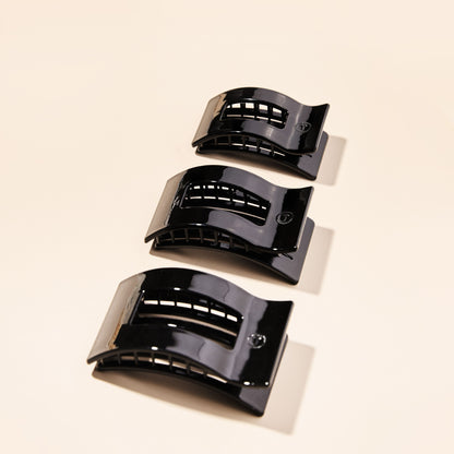 Three black hair clips on a beige background