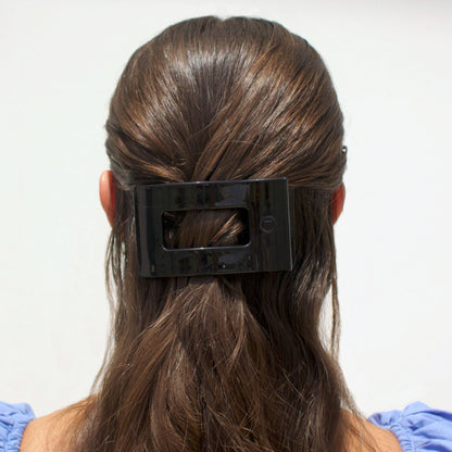 Person with a black hair clip in their brown hair against a white background