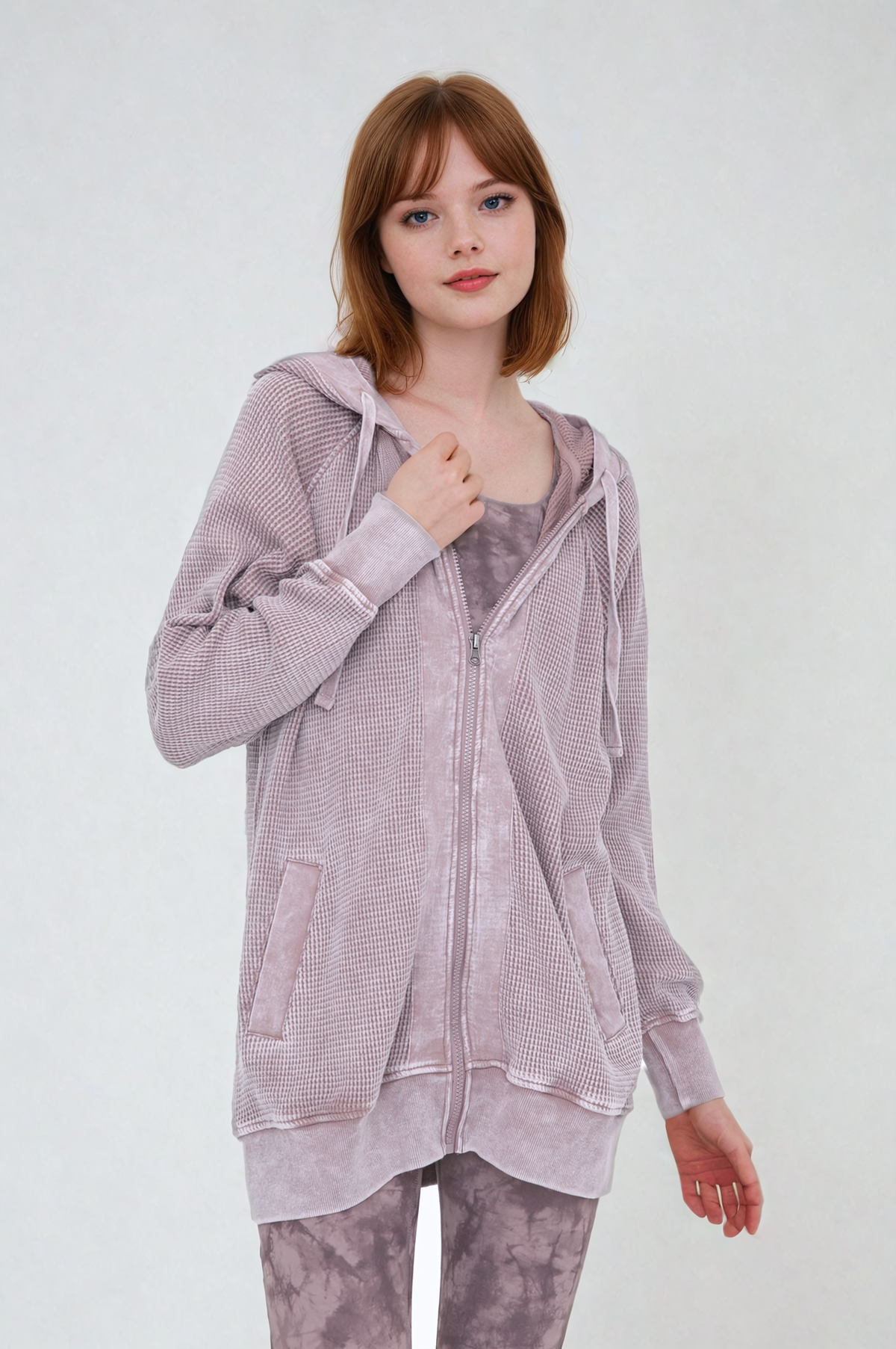 Woman wearing a light purple zip-up hoodie and pants on a white background