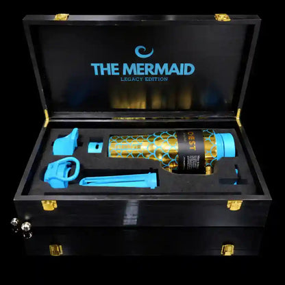 Black wooden box with 'The Mermaid' branding containing a blue and gold bottle and accessories.