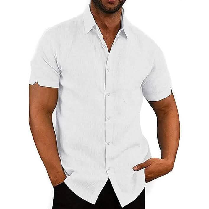 A man wearing a white short-sleeve button-up shirt with a subtle textured weave, paired with black pants, shown against a plain white background.
