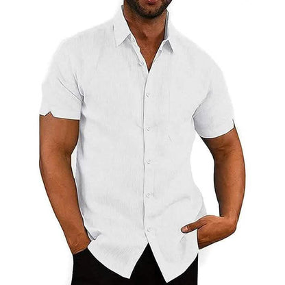 A man wearing a white short-sleeve button-up shirt with a subtle textured weave, paired with black pants, shown against a plain white background.