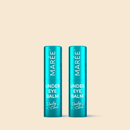 Two teal blue MARÉE Under Eye Balm tubes standing side by side on a solid pale beige background.