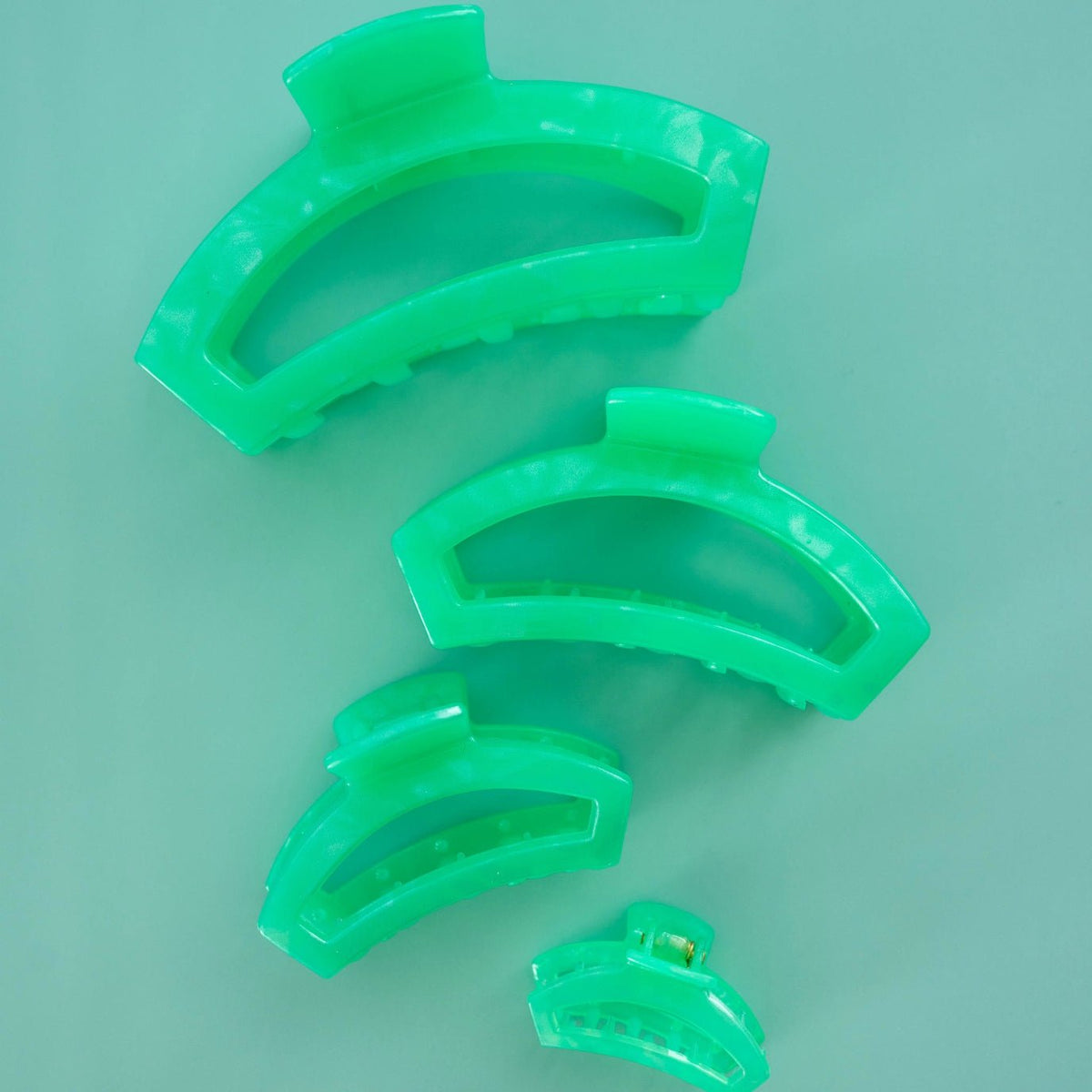 Three green plastic clips on a light green background