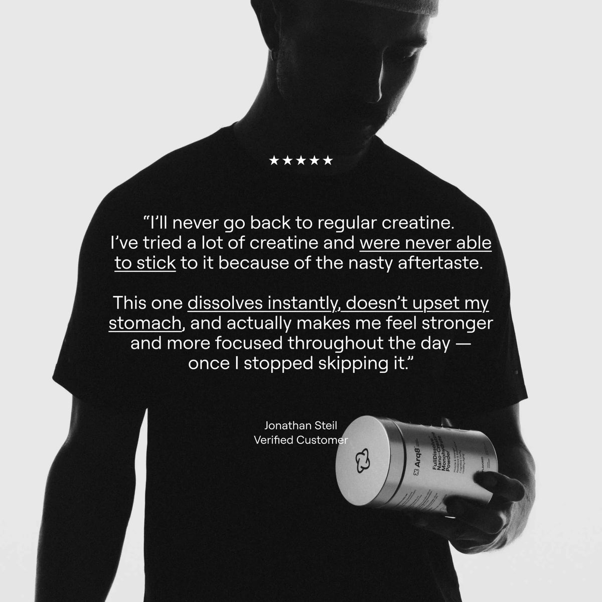 Person holding a supplement container with a customer review on a black t-shirt against a white background