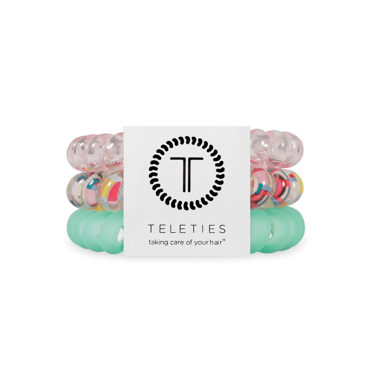 Three Teleties hair elastic bands stacked together with a white paper label in the center. The top band is translucent pink, the middle band is clear with multicolored confetti-like speckles, and the bottom band is translucent mint green.