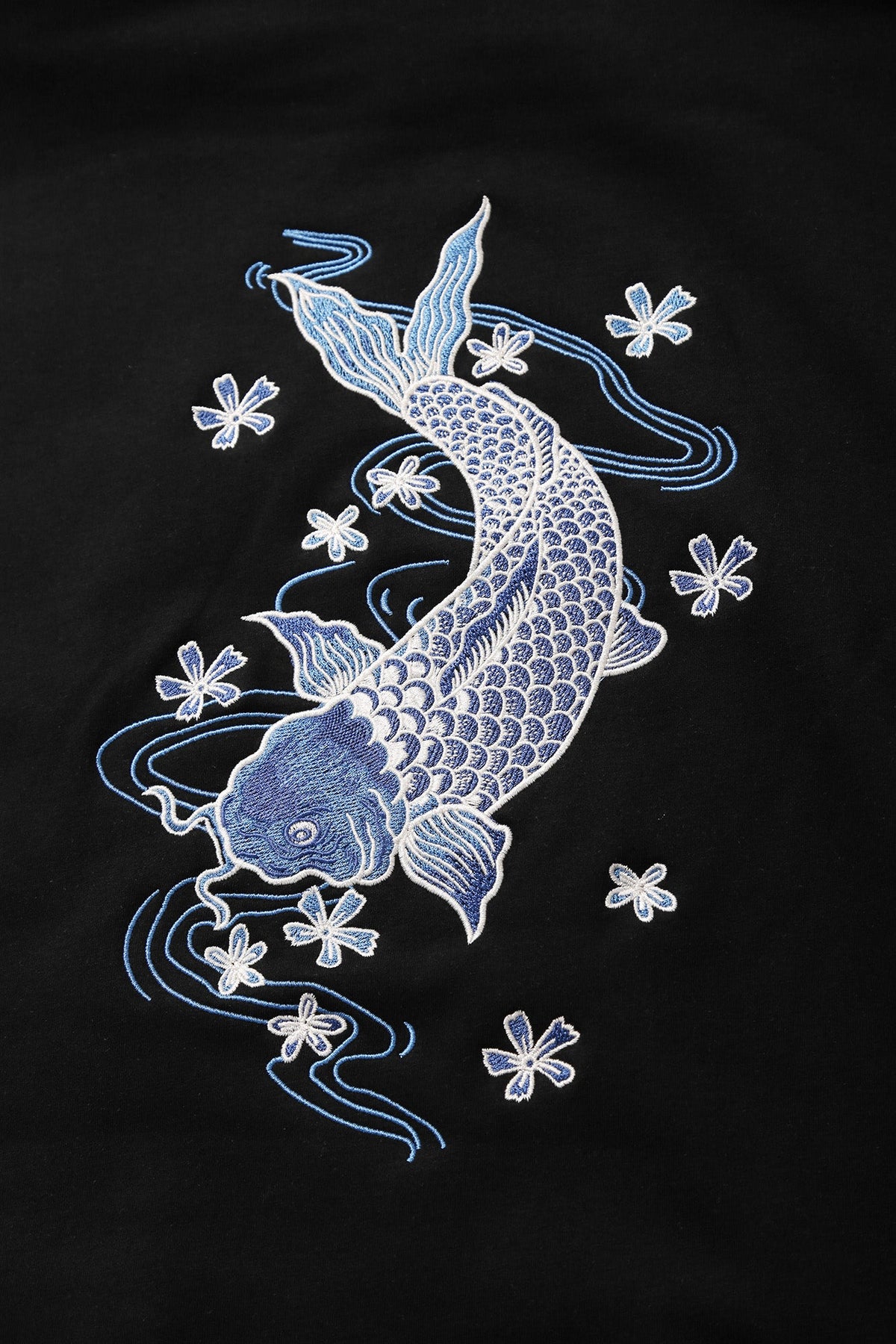 Embroidered design of two koi fish and flowers on a black background