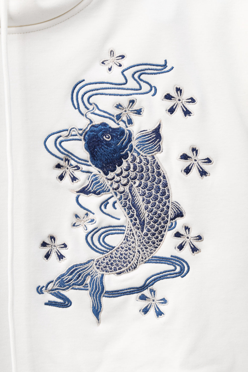 Blue embroidered fish design on a white garment