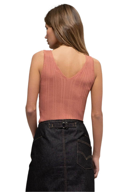 Woman wearing a pink sleeveless top and black denim skirt on a white background