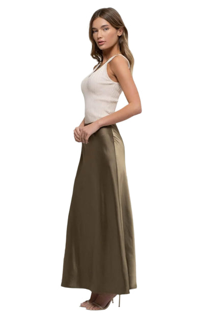 Woman wearing a white top and long brown skirt on a white background