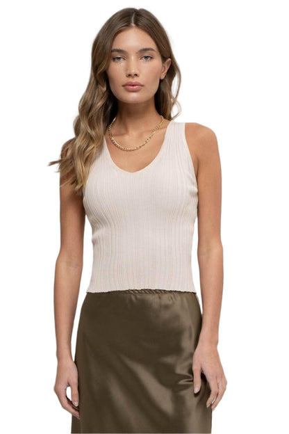 Woman wearing a beige ribbed tank top and brown satin skirt on a white background
