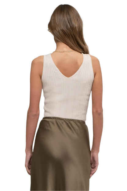 Woman wearing a beige sleeveless top and brown skirt on a white background