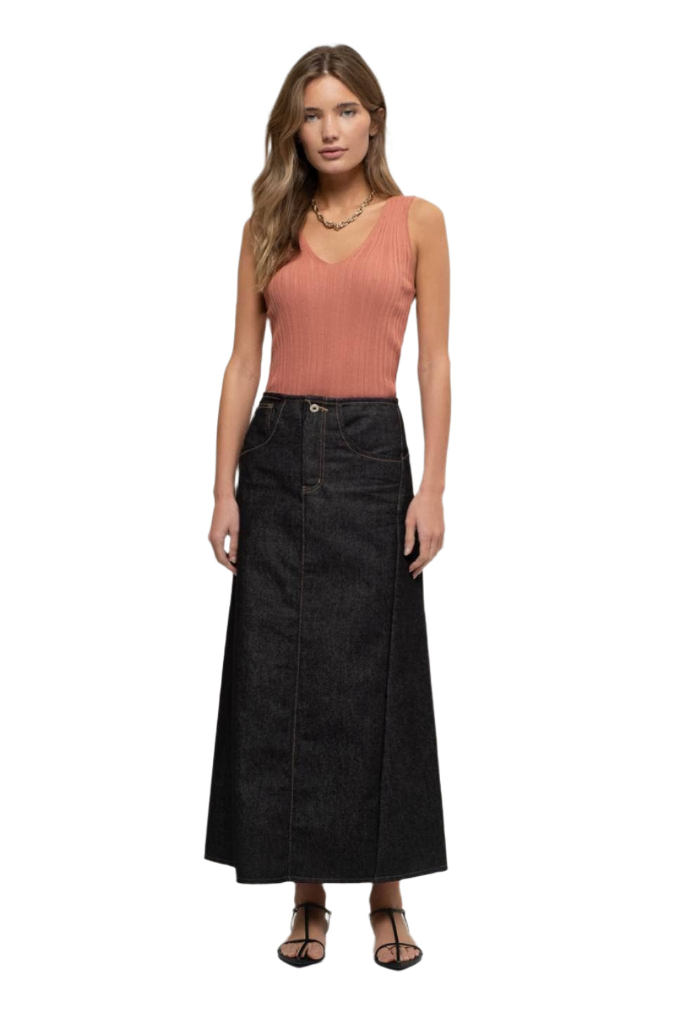 Woman wearing a black denim skirt and peach top on a white background