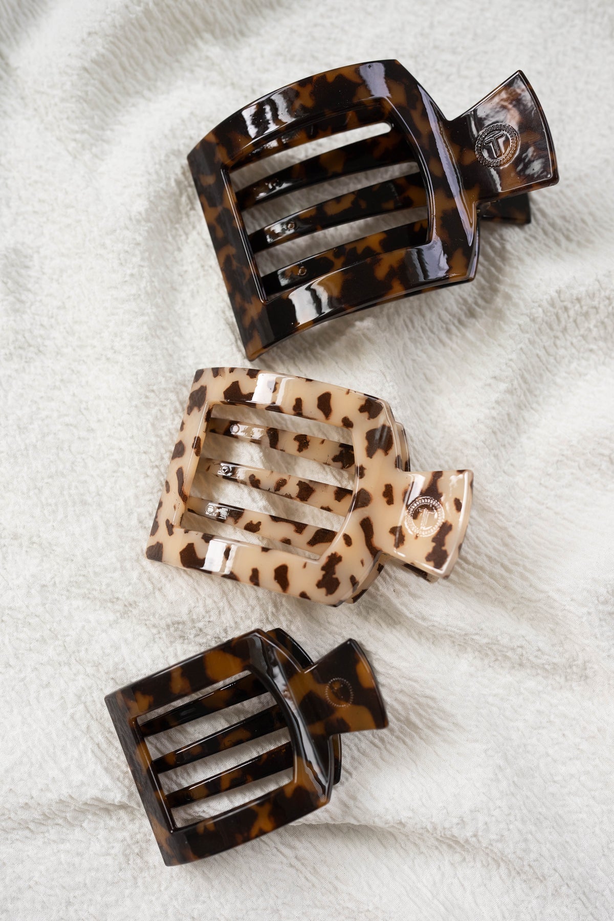 Three tortoiseshell hair clips on a textured white surface