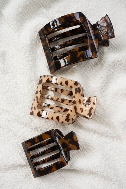 Three tortoiseshell hair clips on a textured white surface