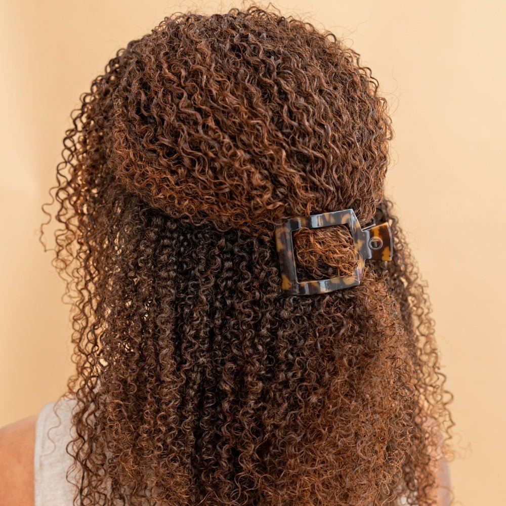 Curly hair with a decorative clip on a beige background