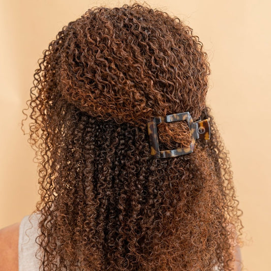 Curly hair with a decorative clip on a beige background
