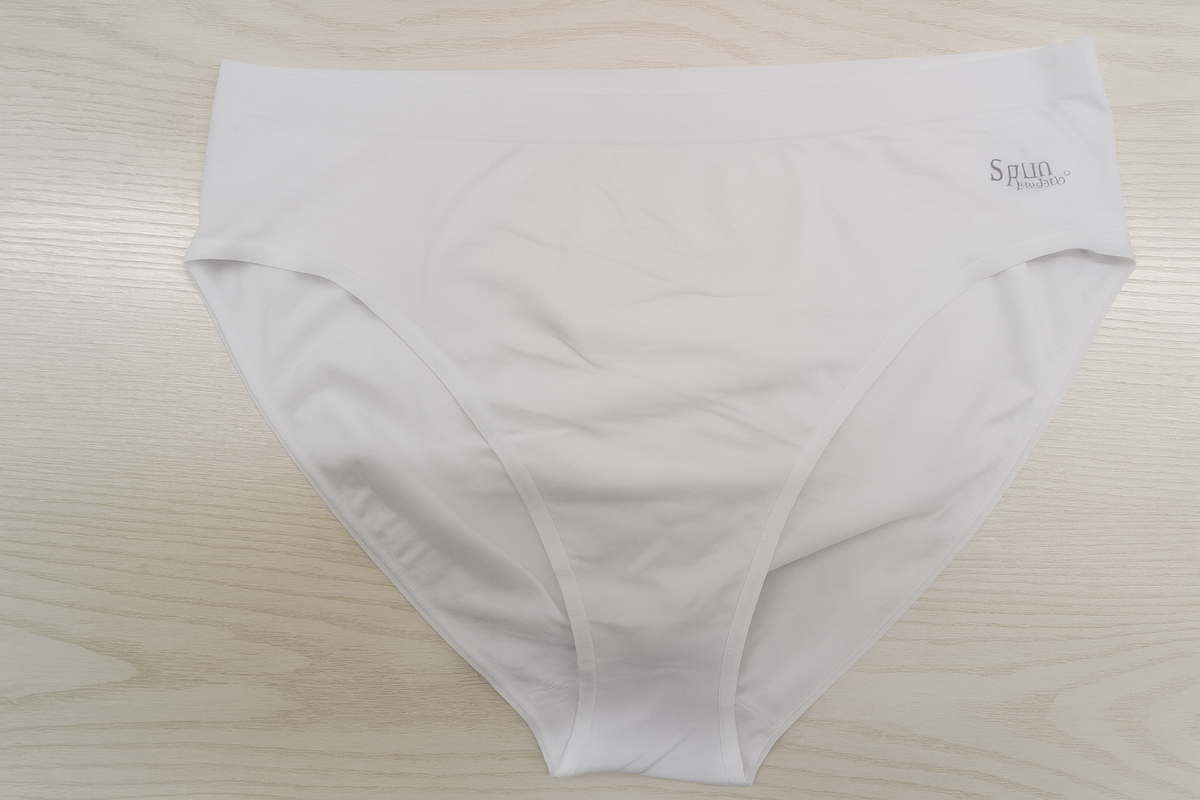 White underwear with a brand logo on a light wooden surface